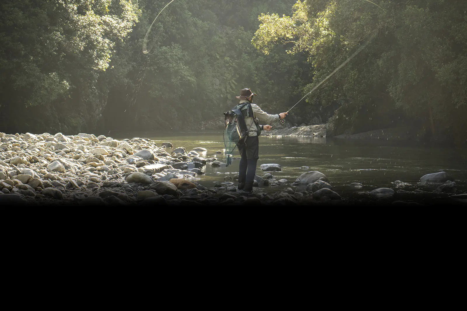 A man standing near the rocky banks of a river while fly fishing near Bryson City, North Carolina.